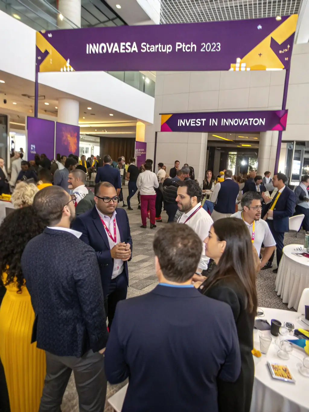 A photograph of the InnovateSA Startup Pitch 2023 event, showcasing a diverse group of attendees networking and engaging with startup founders.
